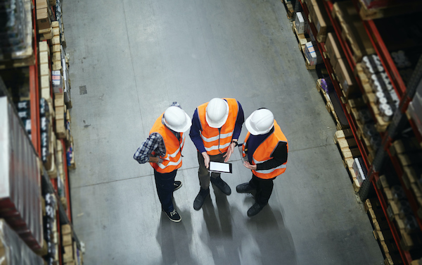 Team of warehouse workers with touchpad making revision of goods