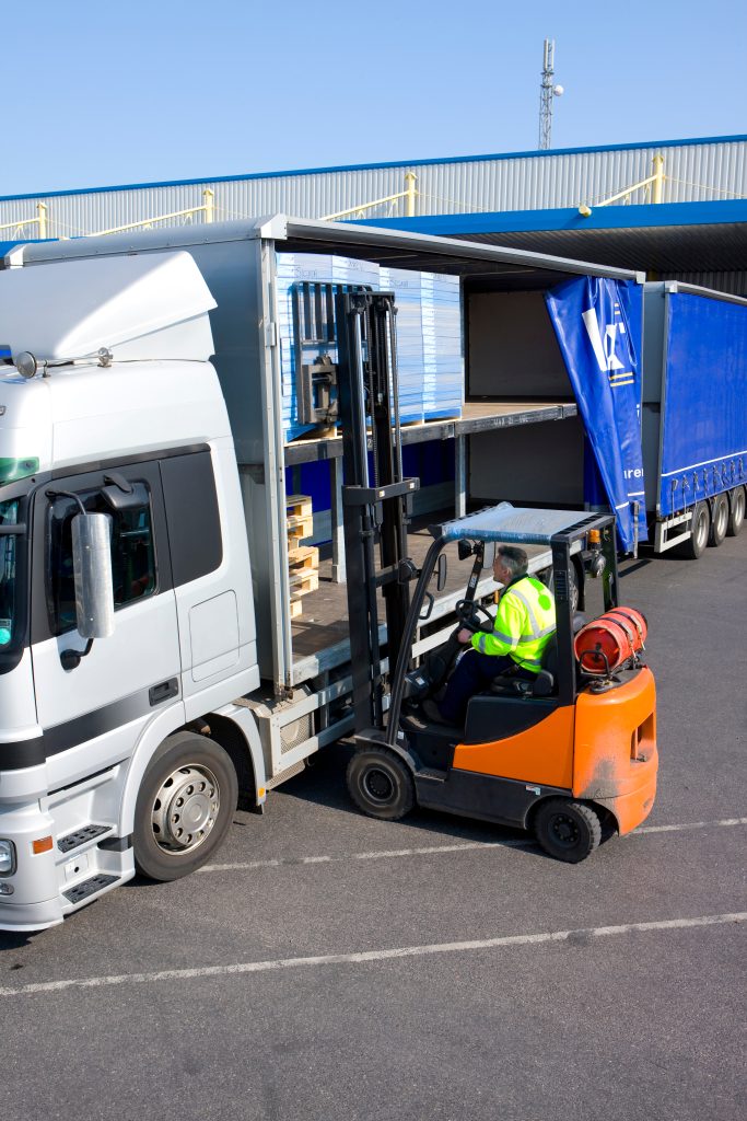 A middle aged worker driving and using the forklif